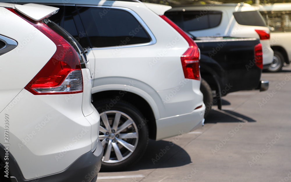 Closeup of rear, back side of white car with  other cars parking in outdoor parking lot in bright sunny day. 