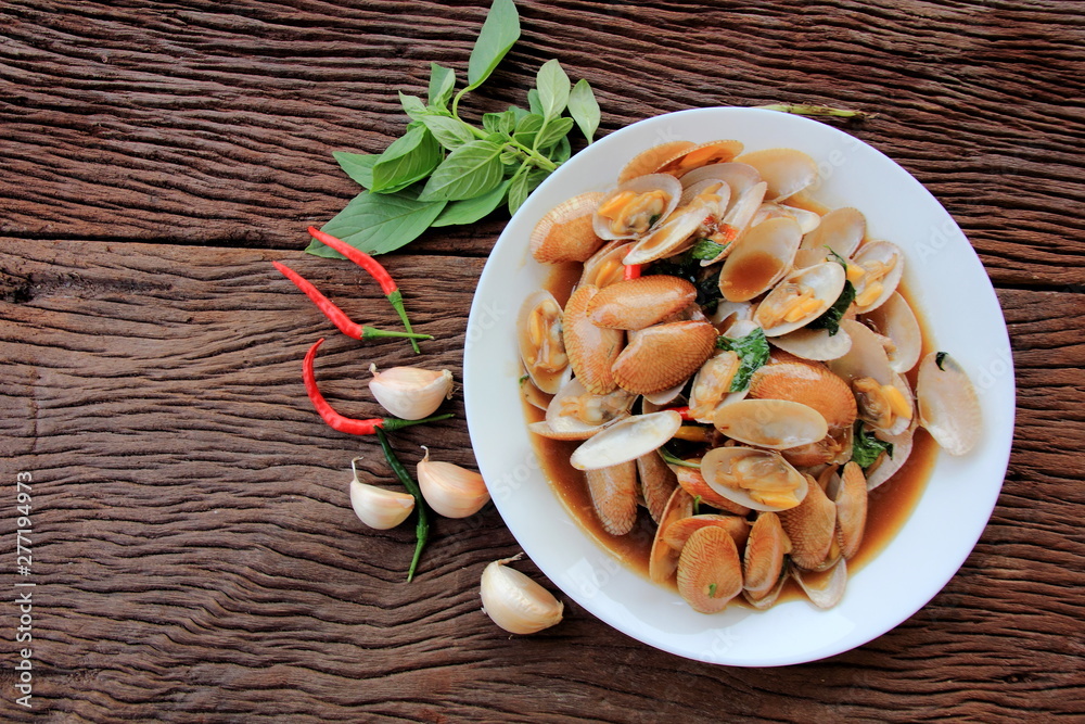 Fototapeta premium Stir fried clam with chili paste and thai basil leaf in white dish,On the wooden, This is thai food cuisine.