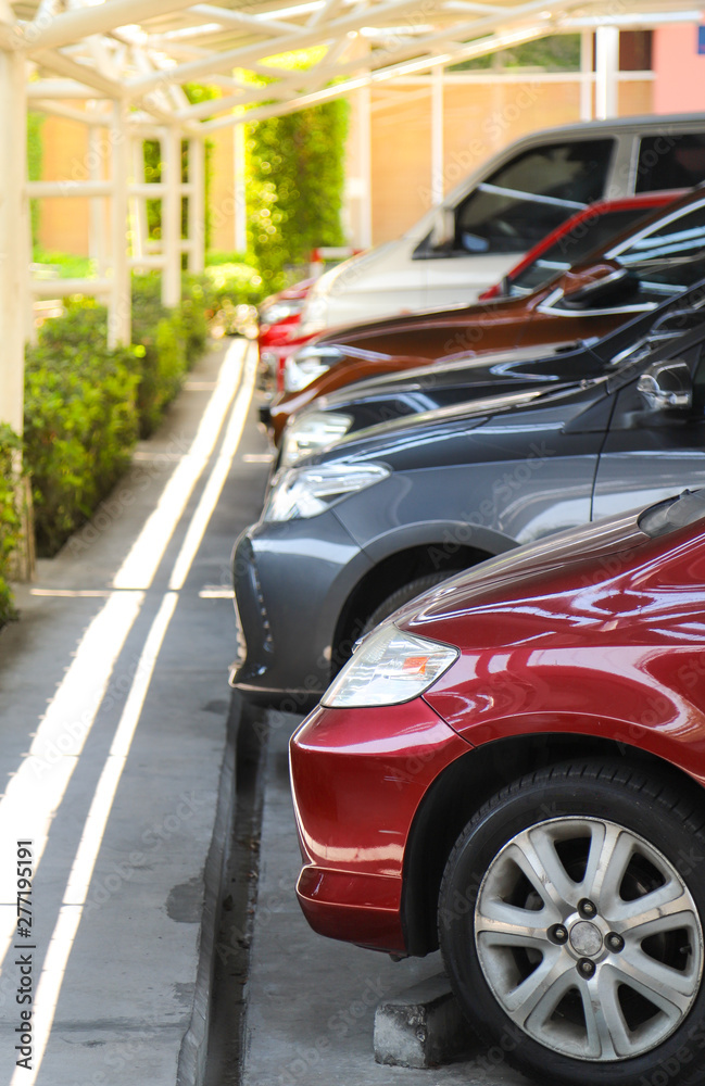 Closeup of front side of red car with  other cars parking in parking lot under roof. vertical view.