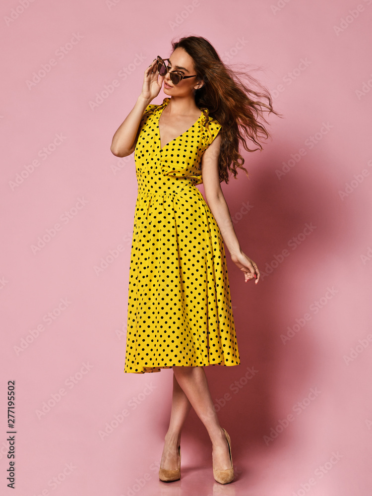 Beautiful girl in a romantic dress smiling pretty on a purple background. Slender curly female model in a yellow polka dot dress Beautiful girl in a romantic dress smiling pretty on a purple background. Slender curly female model in a yellow polka dot dress