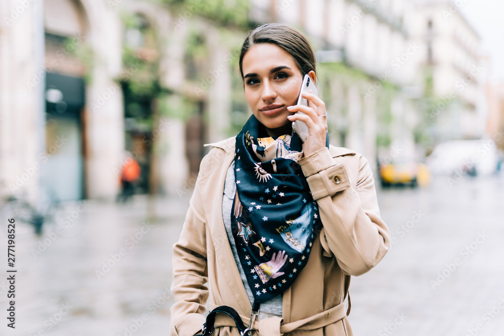Attractive brunette woman talking on mobile phone with client.