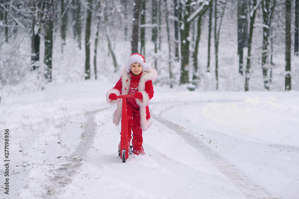 Child dressed  as Santa Claus with gifts in snowy winter outdoors.