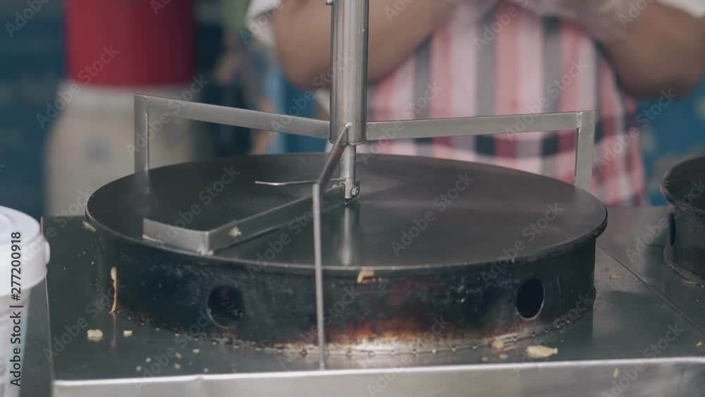 woman waits for modern metal crepe maker heating with drop of water in Asian fast food cafe kitchen closeup woman waits for modern metal crepe maker heating with drop of water in Asian fast food cafe kitchen closeup