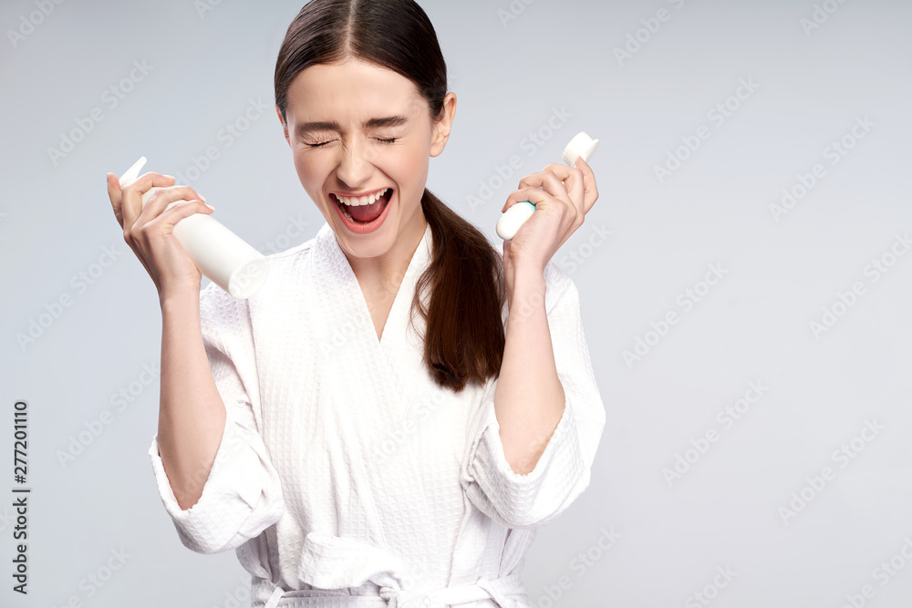 Cute girl holding bottle of cosmetic cream and pore cleansing brush Cute girl holding bottle of cosmetic cream and pore cleansing brush