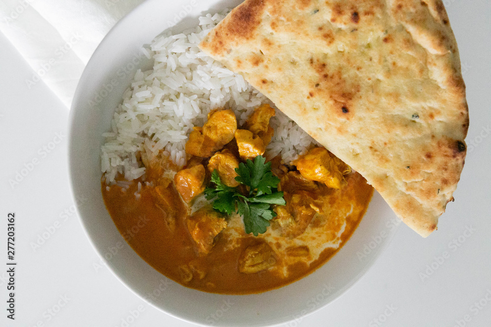 Bowl of Indian Butter Chicken with Jasmine Rice, Homemade Naan, and Cilantro, White Background, Closeup Bowl of Indian Butter Chicken with Jasmine Rice, Homemade Naan, and Cilantro, White Background, Closeup