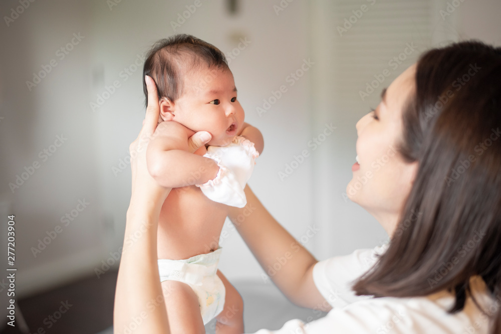 Beautiful mother is playing with her newborn baby in the bedroom. Beautiful mother is playing with her newborn baby in the bedroom.