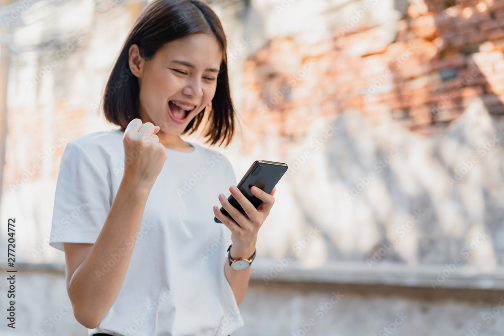 Woman of happy smiling and holding smart phone with amazed for success.The concept of using the phone is essential in everyday life. Woman of happy smiling and holding smart phone with amazed for success.The concept of using the phone is essential in everyday life.