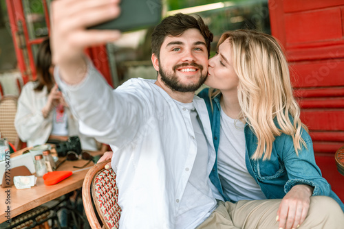 Young couple with smartphone sitting in cafe outdoors
