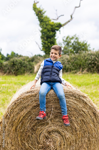 Cute boy on top of a straw bale