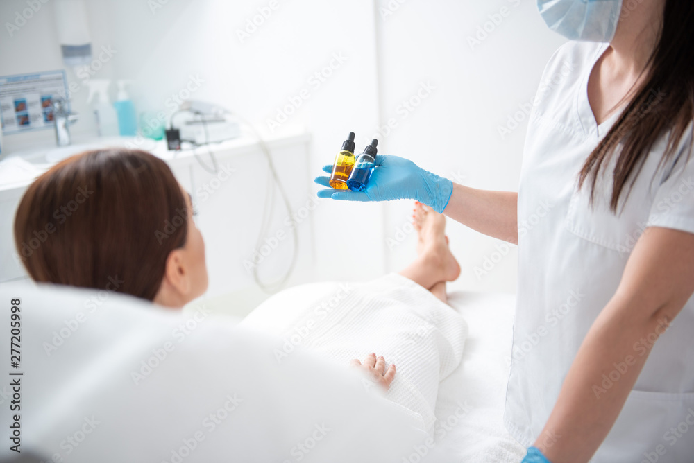 Therapist show two bottles before beauty procedure