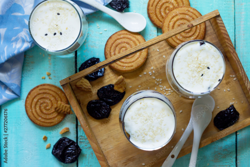 Vegan Dessert with whipped cream, nuts, oatmeal, prunes and sesame in glass glasses on a wooden rustic table. Top view flat lay background. Vegan Dessert with whipped cream, nuts, oatmeal, prunes and sesame in glass glasses on a wooden rustic table. Top view flat lay background.