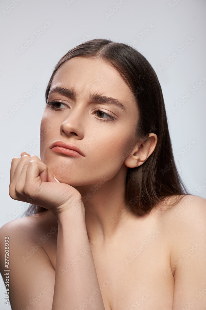 Sad lady posing against light gray background in studio
