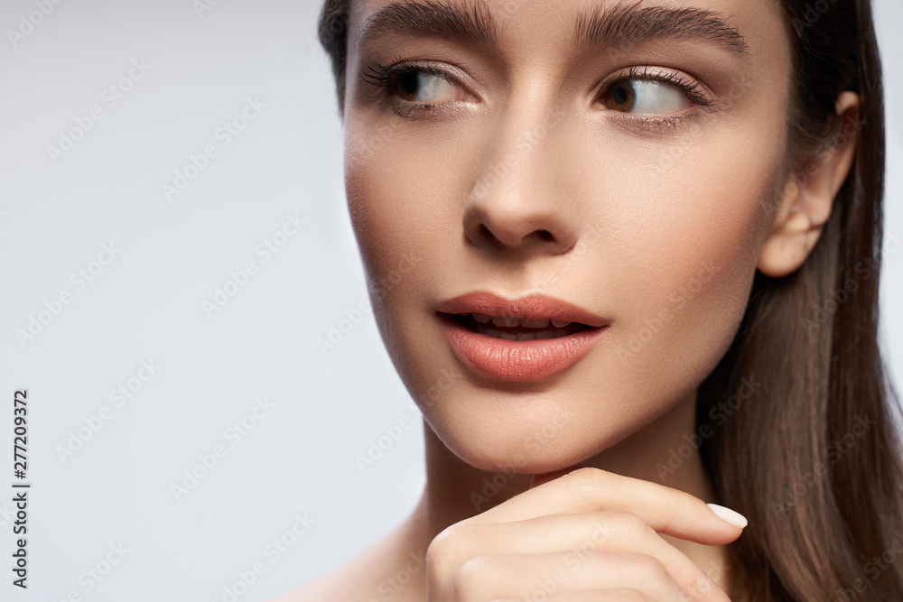 Beautiful woman with natural makeup standing against light gray background Beautiful woman with natural makeup standing against light gray background
