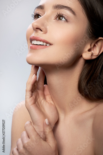 Beautiful young lady with perfect skin keeping hand near face