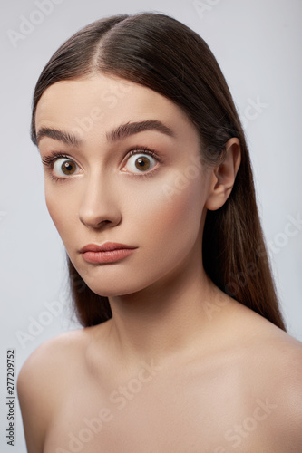 Gorgeous young lady with perfect skin standing against light gray background