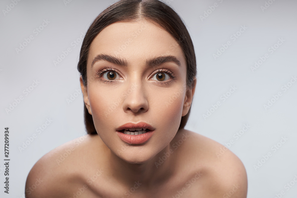 Young lady with beautiful brown eyes posing against light gray background Young lady with beautiful brown eyes posing against light gray background