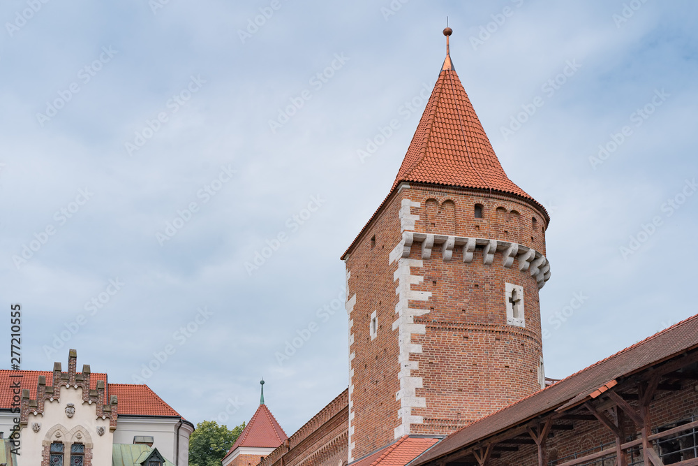Medieval red brick castle defense watchtower against blue sky.