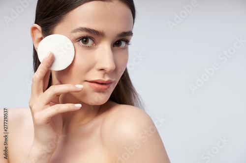 Pretty female with natural makeup holding cosmetic cotton discs