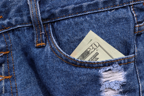Banknote money twenty US dollar in the pocket of blue jeans.