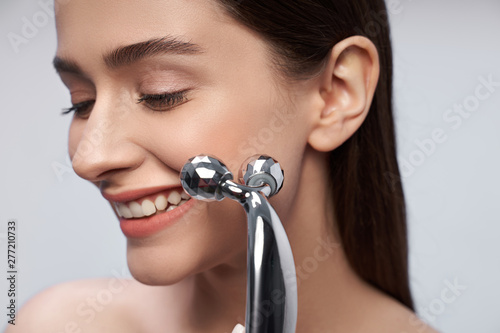 Schilderij op canvas Beautiful lady with perfect skin using platinum face massager