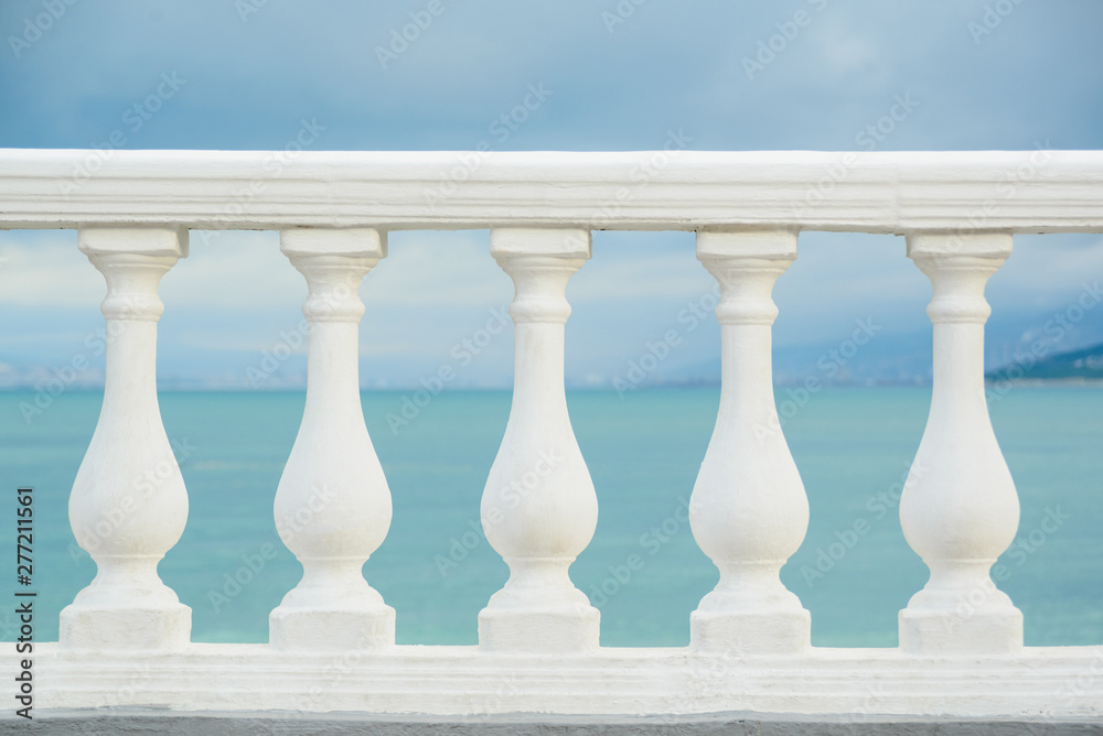 Fototapeta premium classic white balustrade with stone columns on blue sky and black sea water background, stock photo image