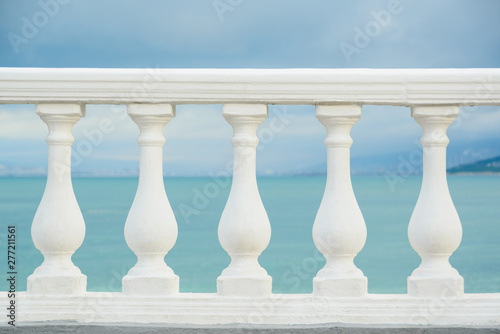 Photo classic white balustrade with stone columns on blue sky and black sea water back