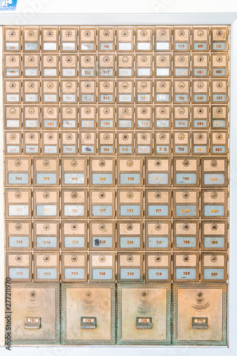 Rows of mid-century modern design post office mailboxes in brass metal.