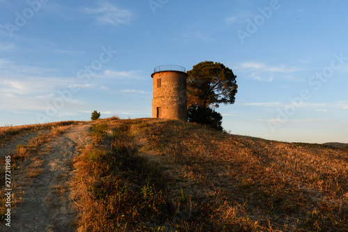 Turm auf Hügel in der Toskana am Abend mit Strohballen