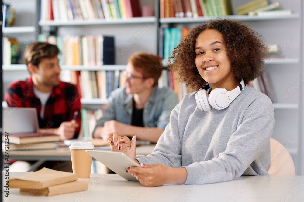 Young cheerful student with tablet getting ready for exam