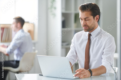 Young pensive businessman reading online information on laptop display © pressmaster
