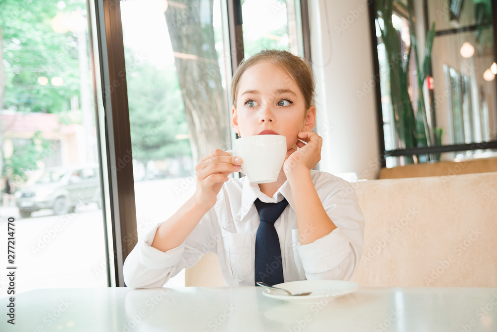 Girl meditates over cup of tea. Business child in tie and shirt Girl meditates over cup of tea. Business child in tie and shirt