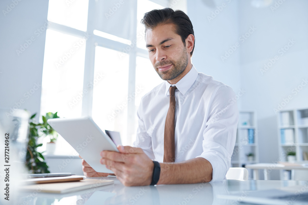 Young businessman with tablet analyzing data in the net