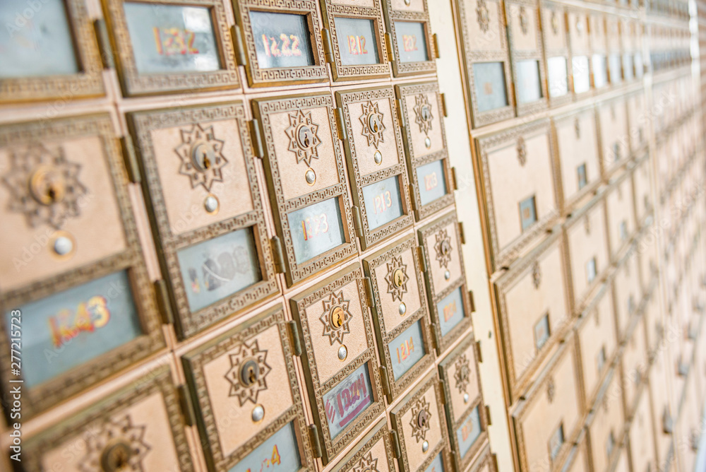 Rows of mid-century modern design post office mailboxes in brass metal.