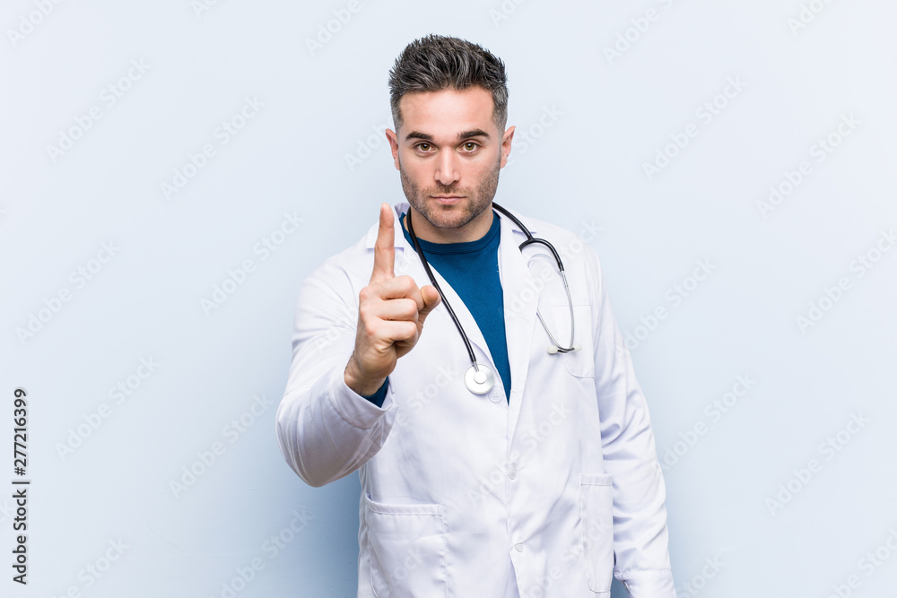 Young handsome doctor man showing number one with finger. Young handsome doctor man showing number one with finger.