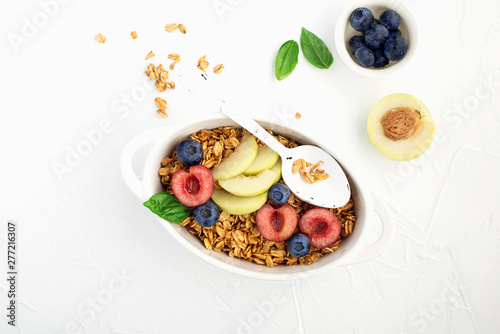 Healthy whole grain breakfast. Baked granola from oatmeal flakes in caramel with fresh berries and fruits of cherries, blueberries, nectarines, basil. Portion. Top view. Balanced diet.