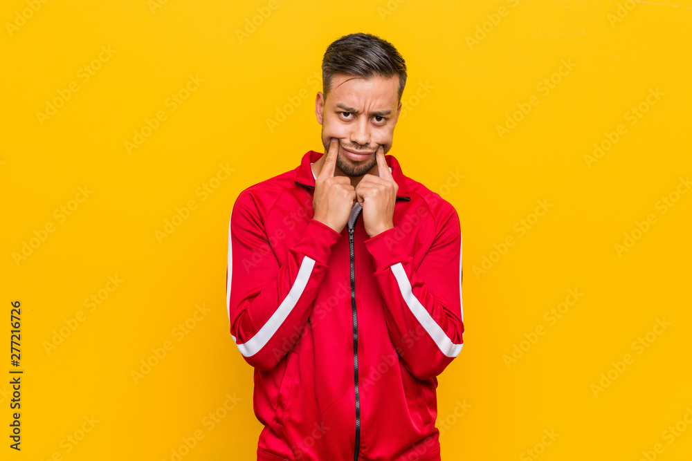 Young filipino fitness man doubting between two options.