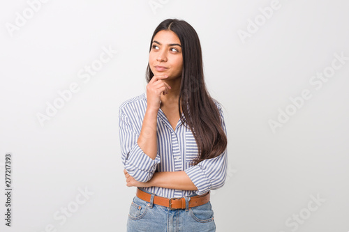 Young pretty arab woman looking sideways with doubtful and skeptical expression.