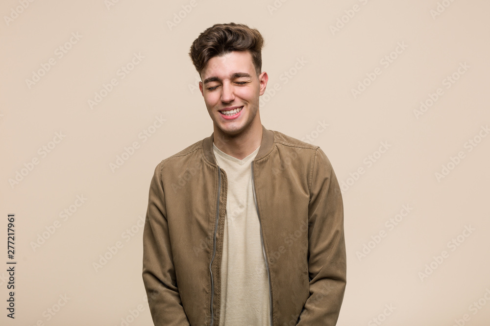 Young caucasian man wearing a brown jacket laughs and closes eyes, feels relaxed and happy. Young caucasian man wearing a brown jacket laughs and closes eyes, feels relaxed and happy.