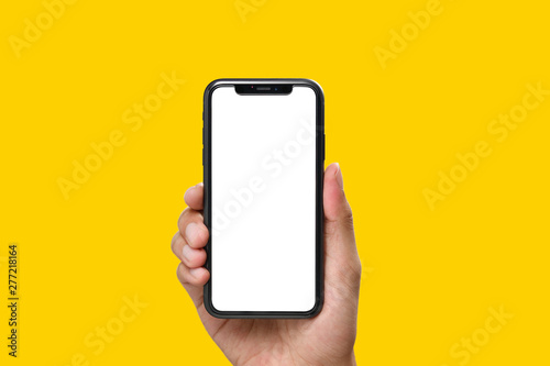 Hand holding the black smartphone with blank screen and modern frame less design on yellow colour background photo