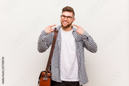 Young modern business man smiles, pointing fingers at mouth.