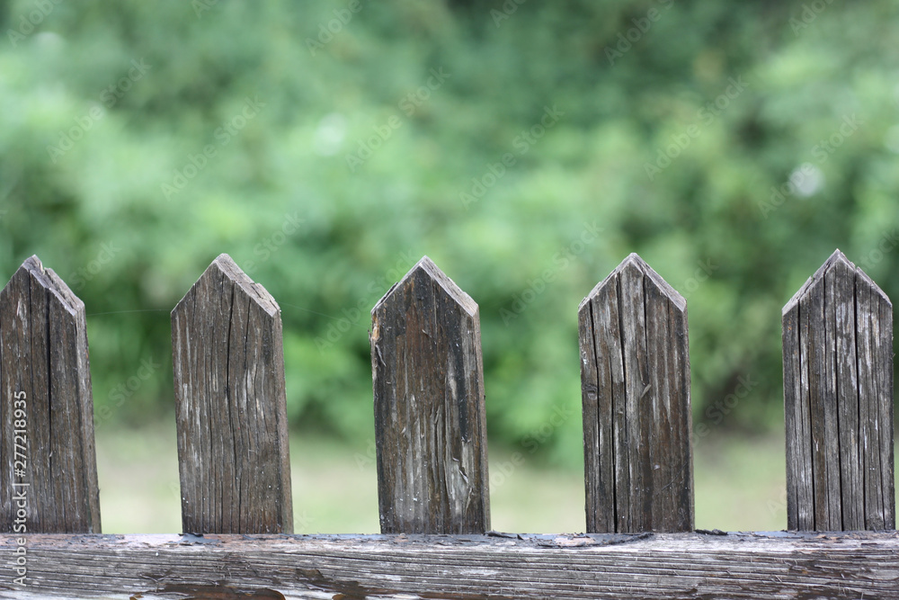 Wooden fence gate pattern with blurred green nature background. Repeating porch wood planks. Wooden fence gate pattern with blurred green nature background. Repeating porch wood planks.