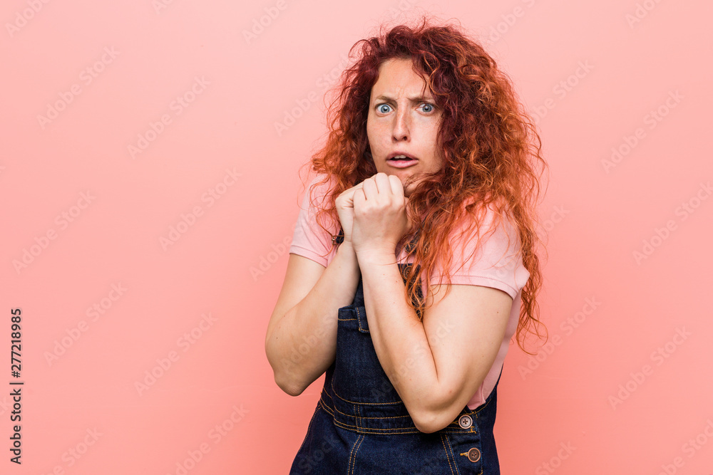 Young pretty ginger redhead woman wearing a jeans dungaree scared and afraid. Young pretty ginger redhead woman wearing a jeans dungaree scared and afraid.