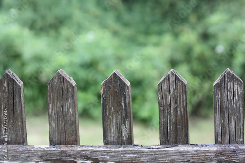 Wooden fence gate pattern with blurred green nature background. Repeating porch wood planks.