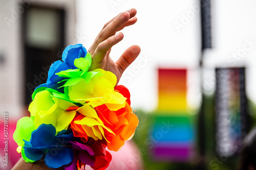 A man's hand is waving in the air and wearing a rainbow bracelet at Gay Pride parade.