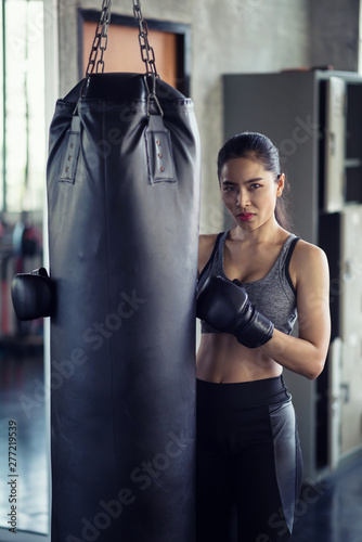 Athletic woman at punching bag in gym © Blanscape