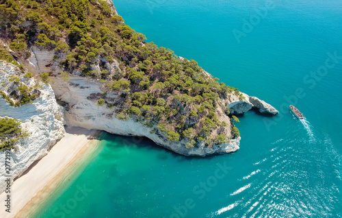 Boat with tourists visiting a groat in Puglia, Italy. Italian holidays in Puglia - Natural park Gargano with beautiful turquoise sea.