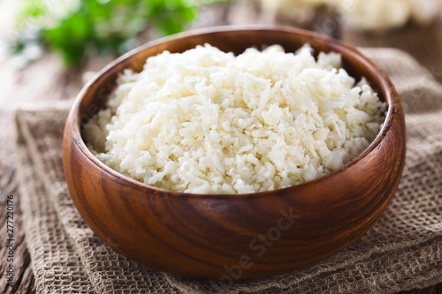 Freshly grated raw cauliflower rice in wooden bowl (Selective Focus, Focus one third into the bowl)