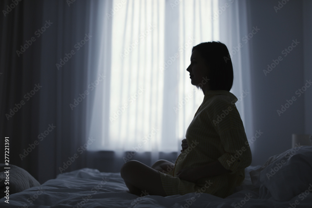 Beautiful pregnant woman sitting on bed at home Beautiful pregnant woman sitting on bed at home
