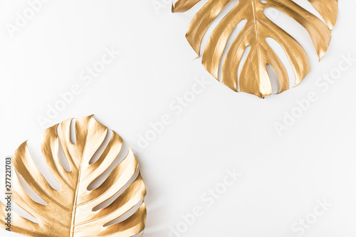 Flat lay of gold tropical palm leaves Monstera on white background. Top view ...