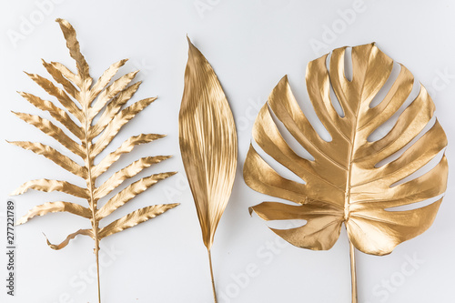 Creative layout with golden tropical leaves on white background. Minimal summ...
